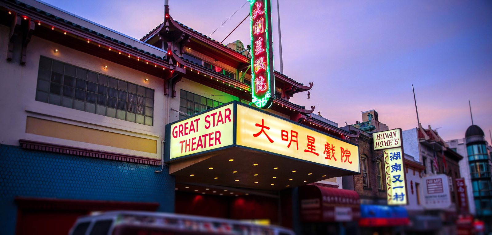 Great Star Theater’s exterior at dusk, with its glowing marquee and vertical neon sign in English and Chinese.